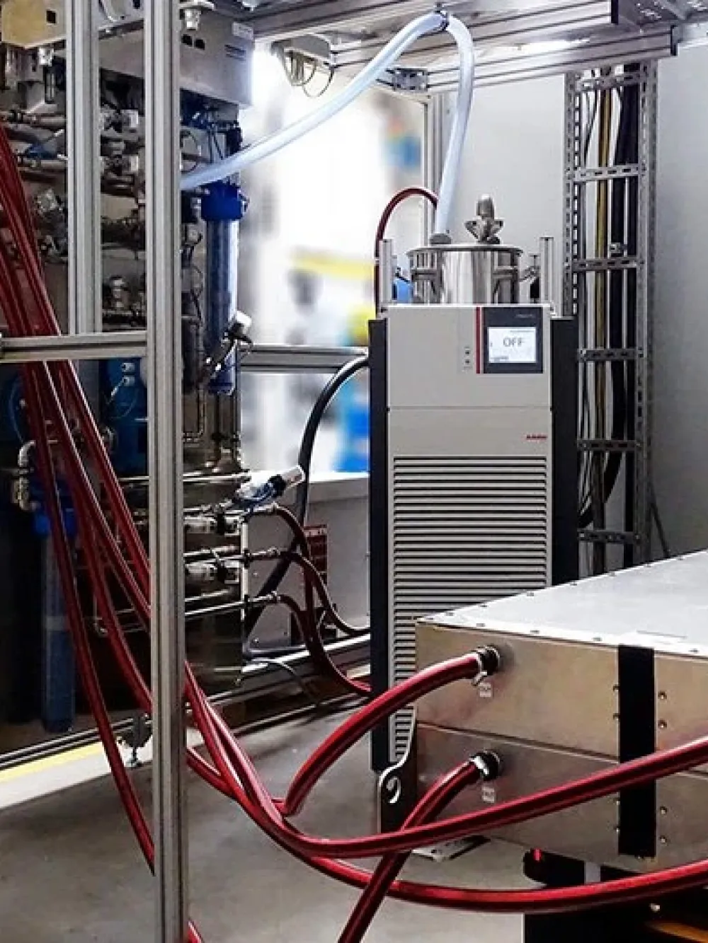 Équipement industriel de test avec de nombreux câbles rouges et orange connectés à un module métallique posé sur une plateforme.