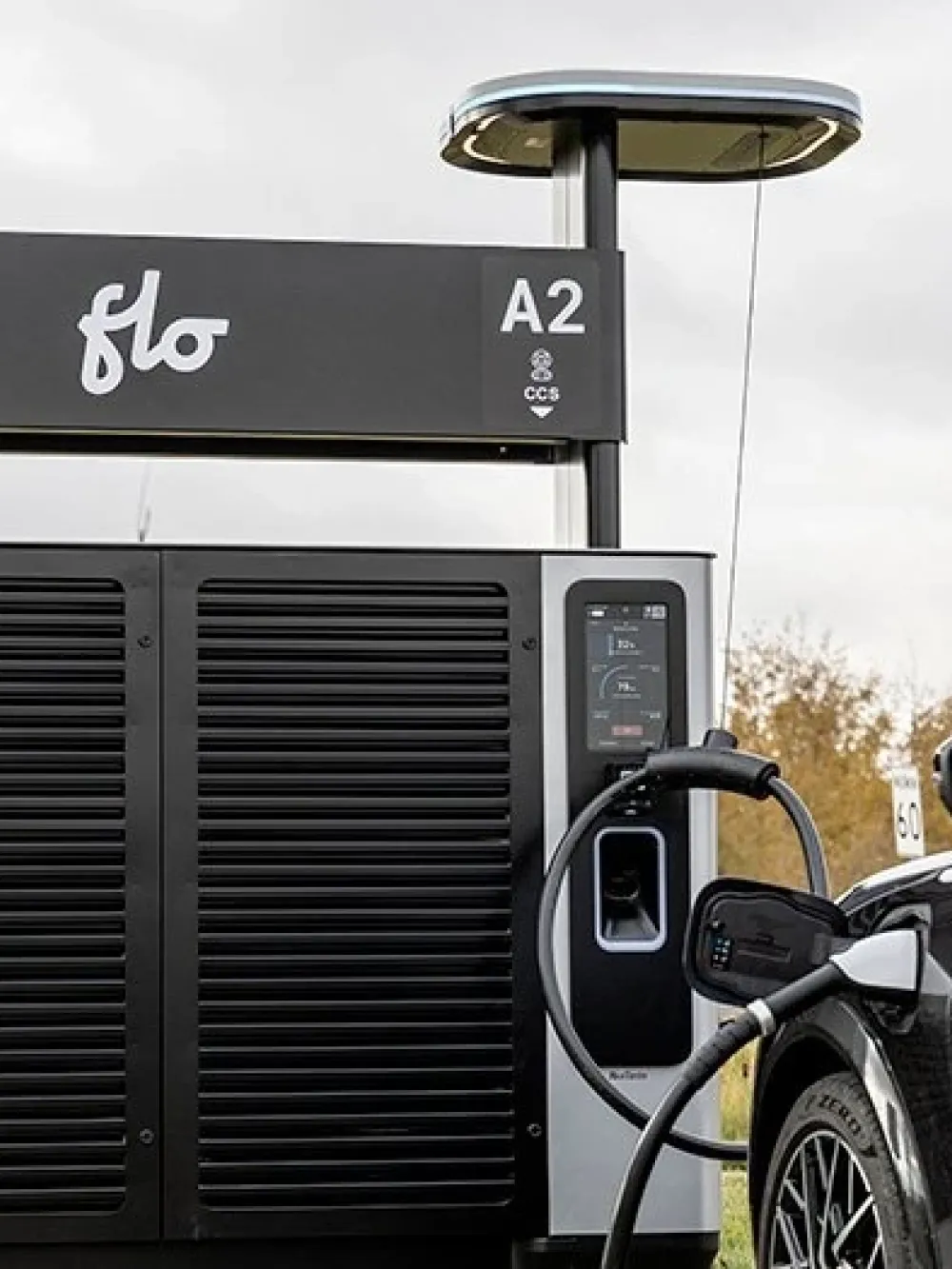 Borne de recharge rapide FLO avec deux stations A1 et A2, utilisée pour recharger une voiture électrique stationnée. 