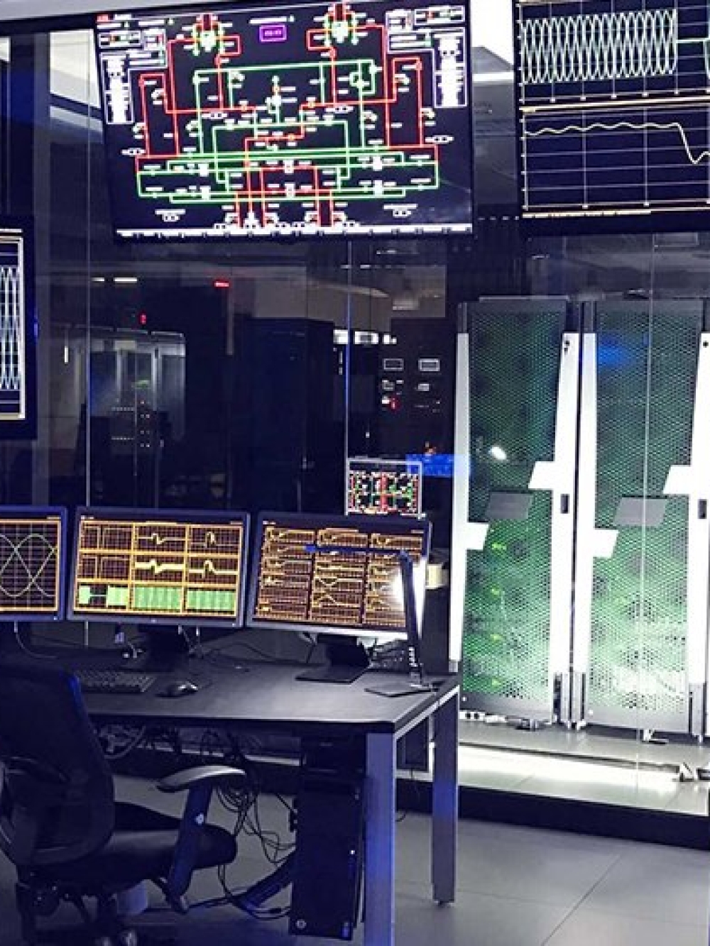 Salle de contrôle remplie d’écrans affichant des données techniques et des schémas électroniques, avec des postes de travail informatiques.