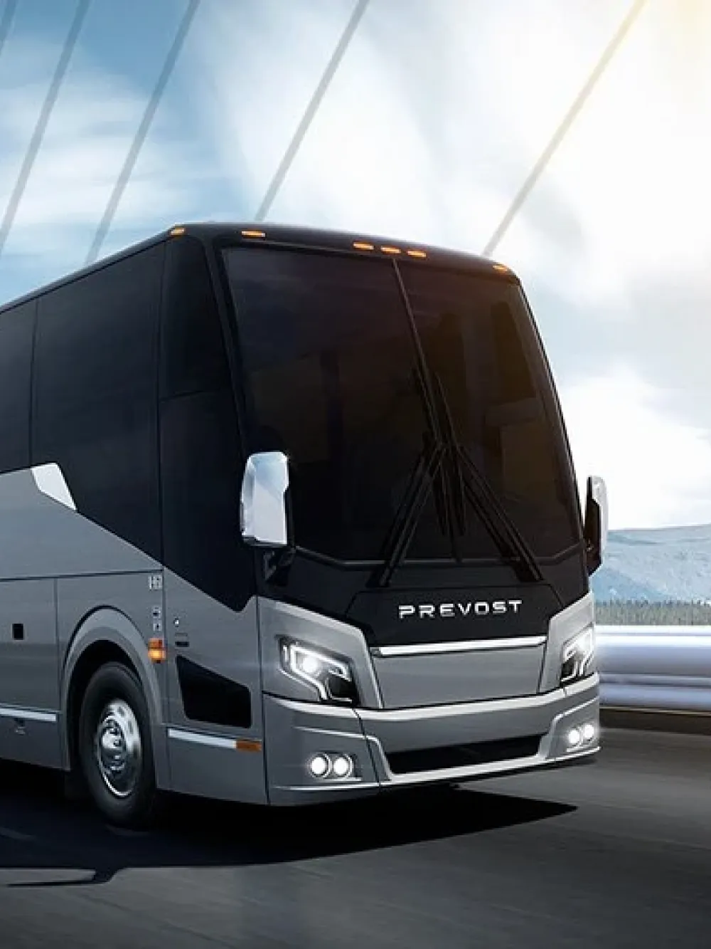 Autocar Prevost roulant sur une route, avec des montagnes en arrière-plan.