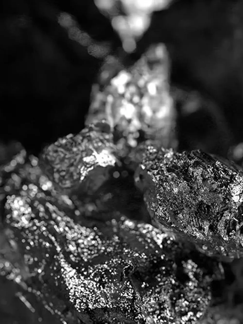 Gros plan sur des fragments de roche sombre et brillante aux reflets métalliques.