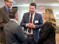 Groupe de personnes en discussion dans une salle de conférence, devant une bannière d’Investissement Québec. 